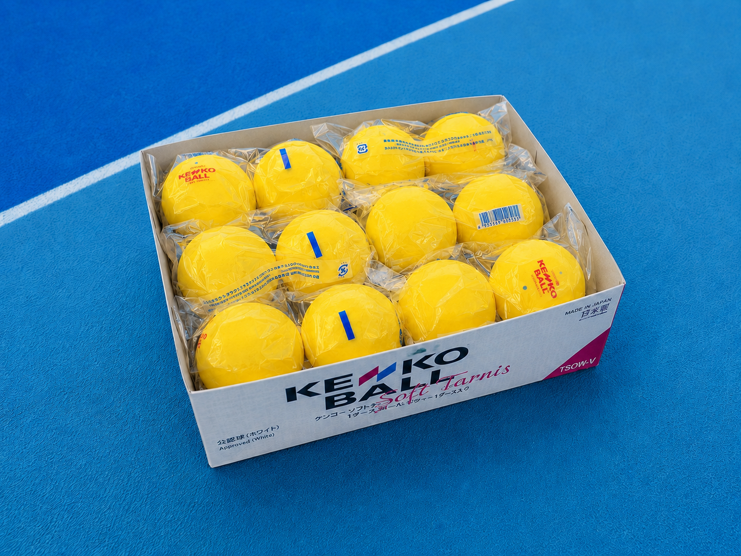 Otwarty karton piłek Kenko Soft Tennis na korcie